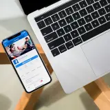 Smartfon z otwartą aplikacją Facebook obok laptopa.
