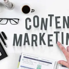 Content SEO Manager do czego służy? Planowanie i tworzenie treści, by przyciągnąć odbiorców. Na biurku klawiatura, okulary, kawa i notatnik.