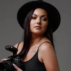 Kobieta w kapeluszu z aparatem Nikon, idealna inspiracja, jak pozować do zdjęć na Instagram.