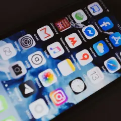 Ekran smartfona z ikonami aplikacji, w tym Facebook. Chcesz wiedzieć, jak sprawdzić czyjś numer telefonu na Facebooku?