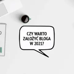 Na biurku leży laptop, notatnik i filiżanka kawy. Dymek z tekstem "Czy warto założyć bloga w 2021?" sugeruje, że to pytanie o założenie bloga na Facebooku.
