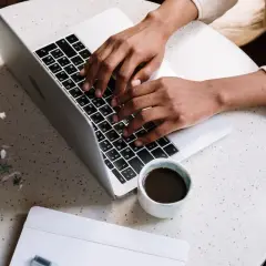 Osoba pisze na laptopie, planując, jak zarabiać na blogu. Obok kawa i notatnik.