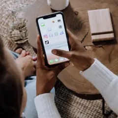 Osoba trzyma smartfon z ikonami aplikacji, w tym Facebooka. Dowiedz się, jak zablokować zdjęcia na Facebooku, aby chronić swoją prywatność.