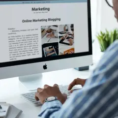 Mężczyzna pisze na klawiaturze, przeglądając artykuł o marketingu online. Zastanawia się, gdzie prowadzić bloga, by dotrzeć do szerszej publiczności.