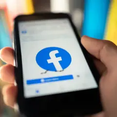 Dłoń trzyma smartfon z ekranem logowania Facebooka. Chcesz wiedzieć, jak usunąć Facebook na stałe?