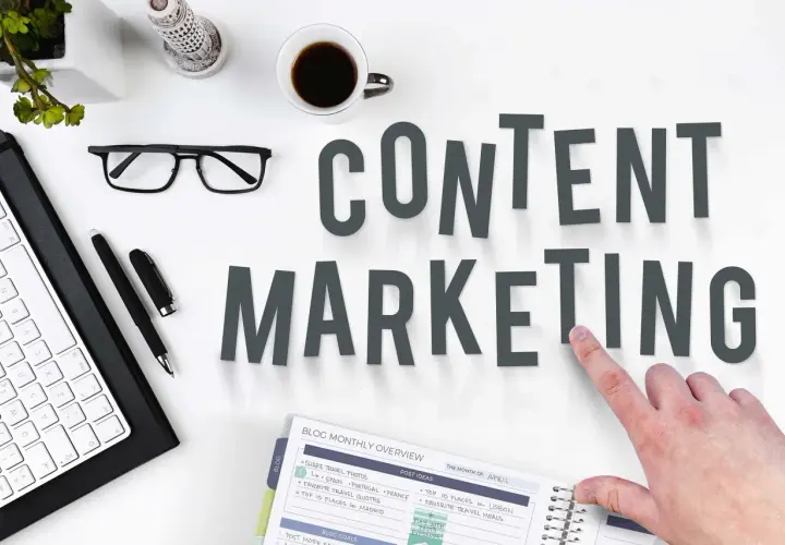 Content SEO Manager do czego służy? Planowanie i tworzenie treści, by przyciągnąć odbiorców. Na biurku klawiatura, okulary, kawa i notatnik.