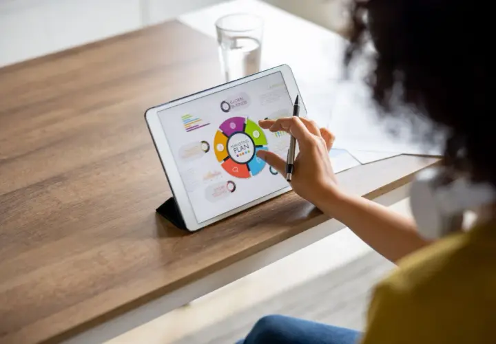 Kobieta pracuje nad planem marketingowym na tablecie, angażując się w **content co creation**.