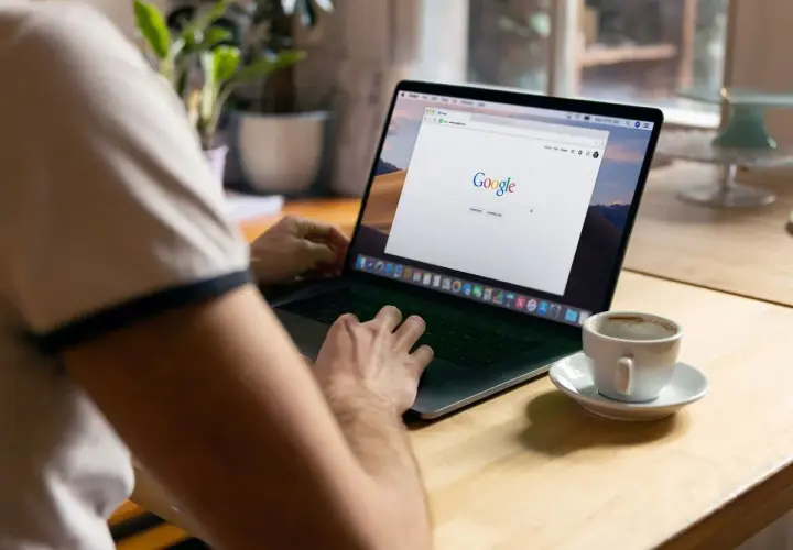 Osoba przy kawie uczy się, jak zmniejszyć stronę w przeglądarce na laptopie.