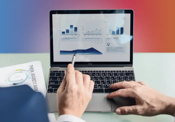 Analiza danych na laptopie. Ręka wskazuje na wykres, a obok leży dokument "Global Business Markets". To pokazuje, content co to znaczy w praktyce.