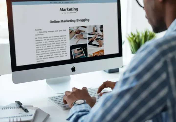 Mężczyzna pisze na klawiaturze, przeglądając artykuł o marketingu online. Zastanawia się, gdzie prowadzić bloga, by dotrzeć do szerszej publiczności.