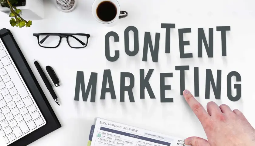 Content SEO Manager do czego służy? Planowanie i tworzenie treści, by przyciągnąć odbiorców. Na biurku klawiatura, okulary, kawa i notatnik.