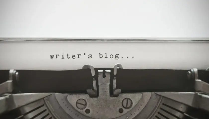 Zbliżenie na starą maszynę do pisania z tekstem "writer's blog..." na papierze.