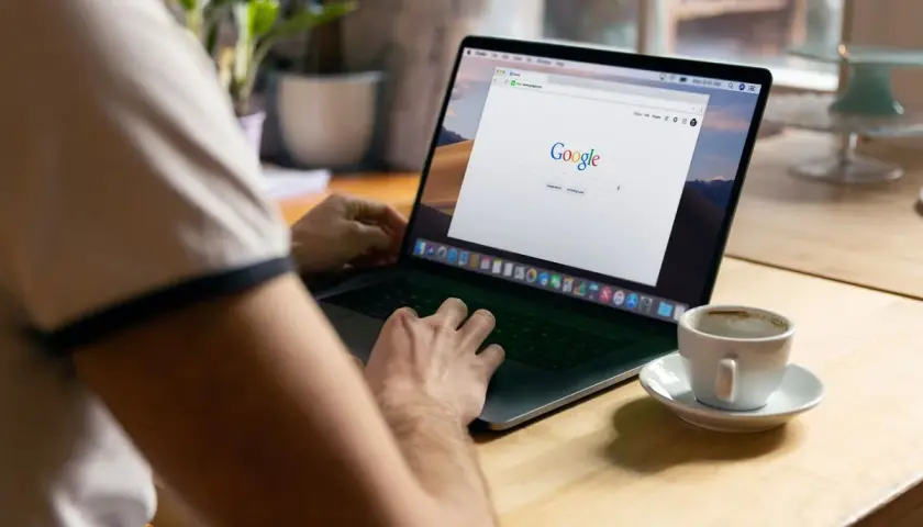Osoba przy kawie uczy się, jak zmniejszyć stronę w przeglądarce na laptopie.