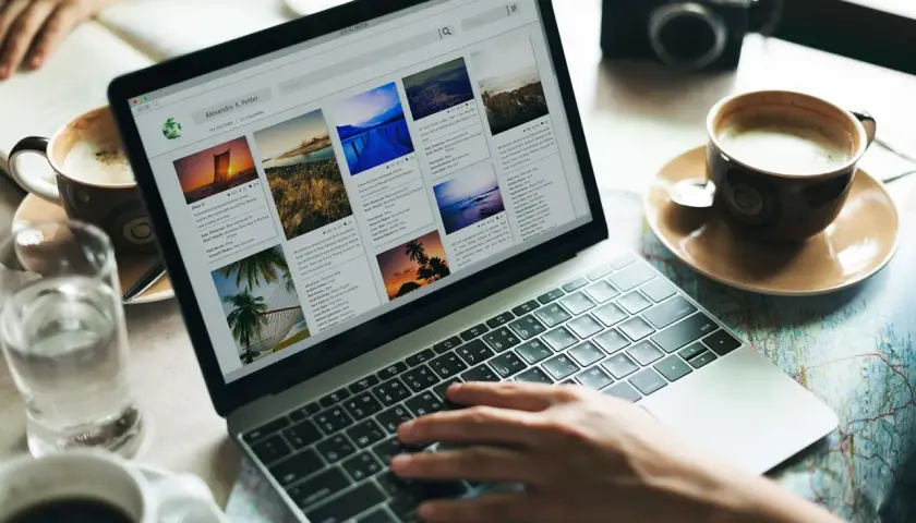 Osoba pisze na laptopie, przeglądając wpisy na blogu podróżniczym. Inspiracja, jak stworzyć blog osobisty na FB.