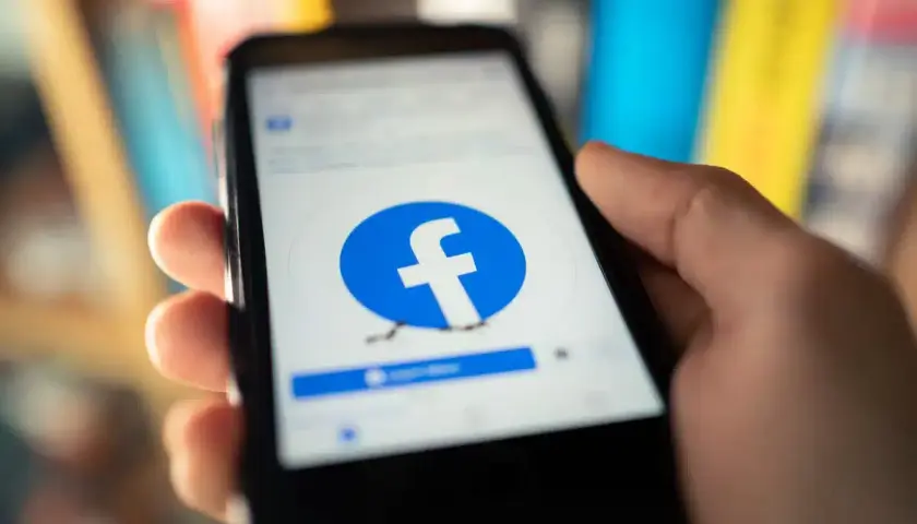 Dłoń trzyma smartfon z ekranem logowania Facebooka. Chcesz wiedzieć, jak usunąć Facebook na stałe?