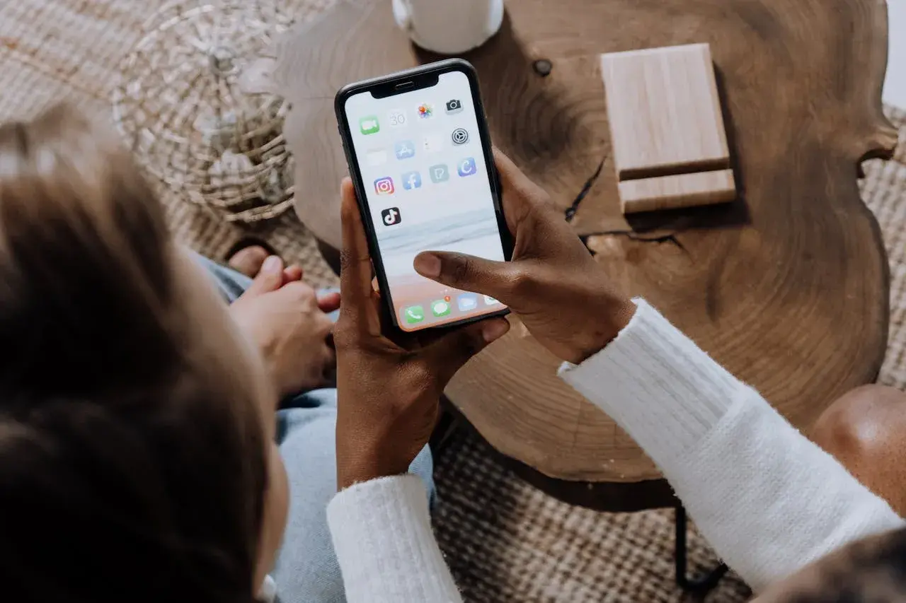 Osoba trzyma smartfon z ikonami aplikacji, w tym Facebooka. Dowiedz się, jak zablokować zdjęcia na Facebooku, aby chronić swoją prywatność.