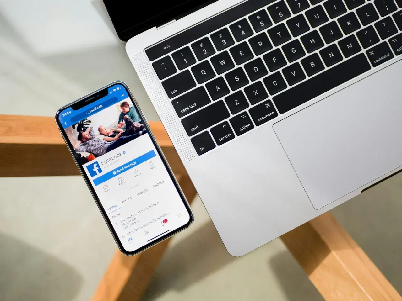 Smartfon z otwartą aplikacją Facebook obok laptopa.