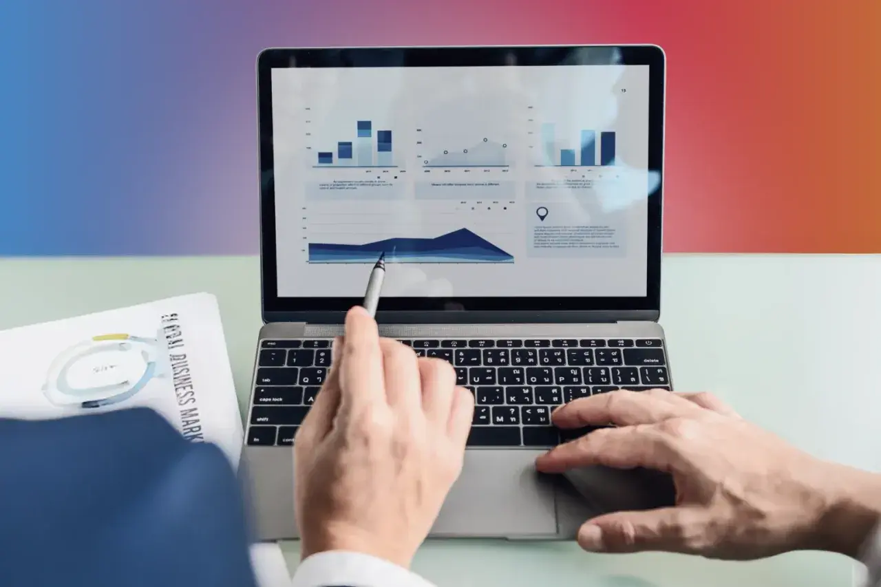 Analiza danych na laptopie. Ręka wskazuje na wykres, a obok leży dokument "Global Business Markets". To pokazuje, content co to znaczy w praktyce.